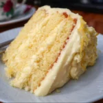Slice of dreamy lemon cheesecake cake with cream cheese frosting on a white plate