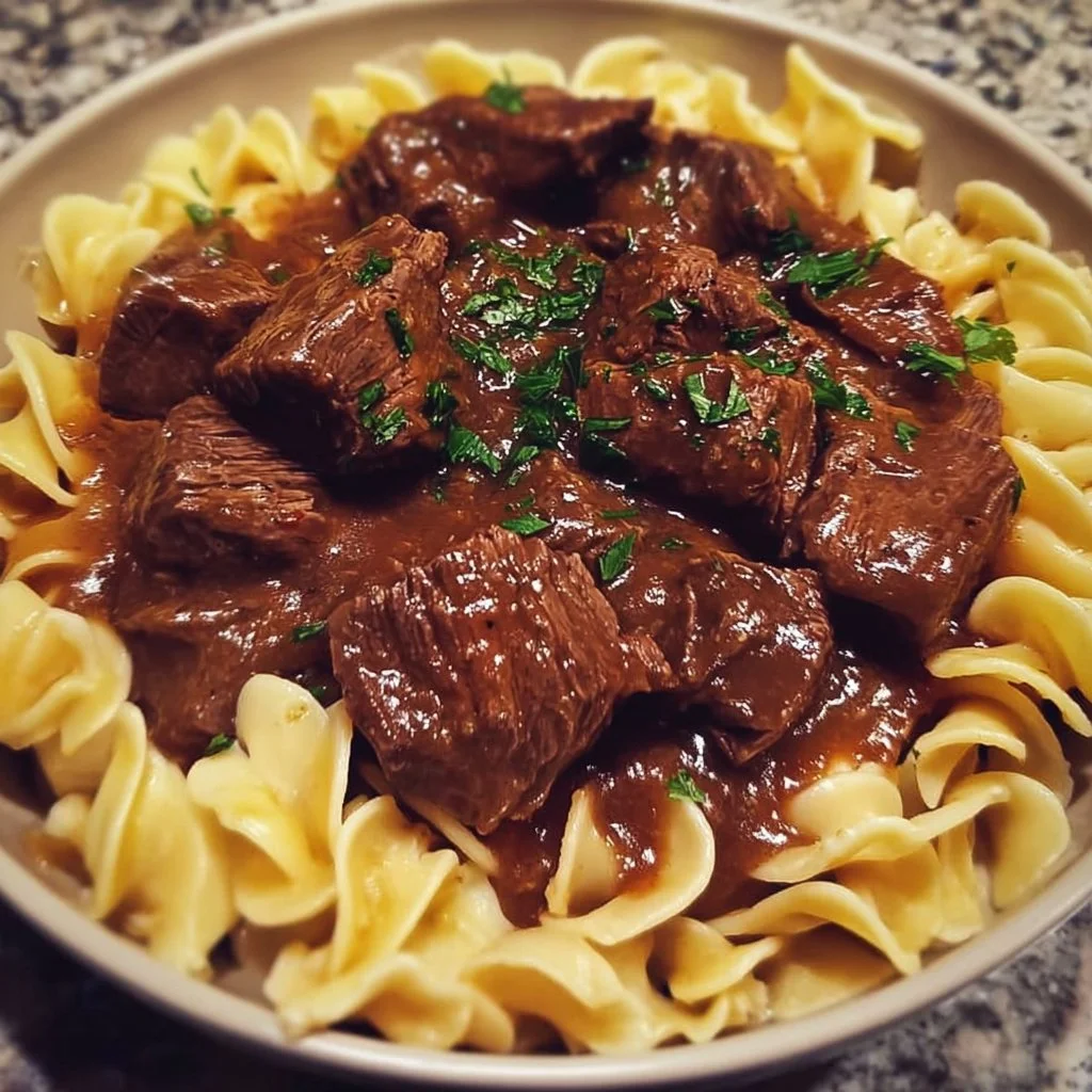 Crockpot beef tips and noodles served in a bowl garnished with parsley