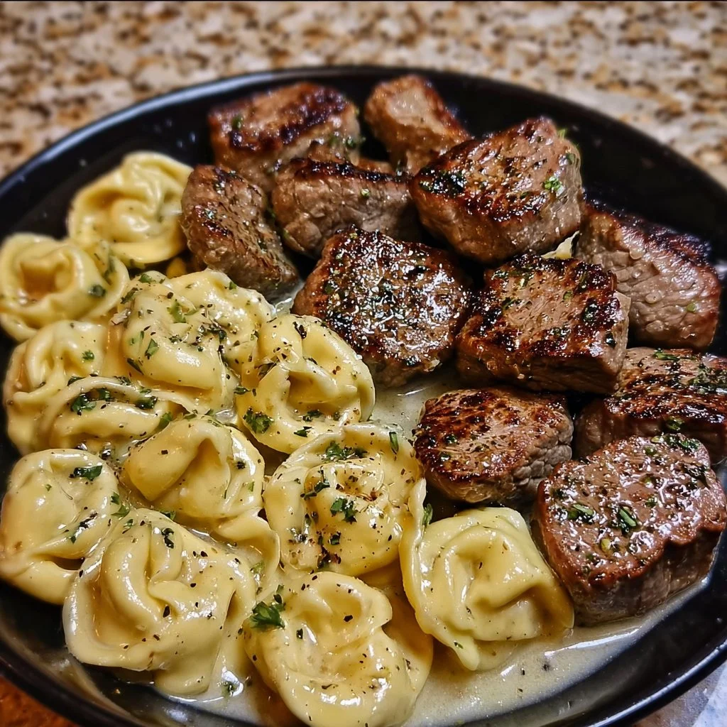 Delicious Garlic Butter Steak Bites served with creamy Alfredo tortellini on a plate.