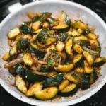 Delicious sautéed zucchini garnished with herbs and spices in a skillet.