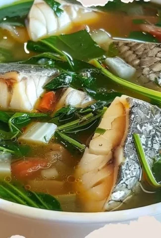 Bowl of delicious fish soup with fresh vegetables and herbs