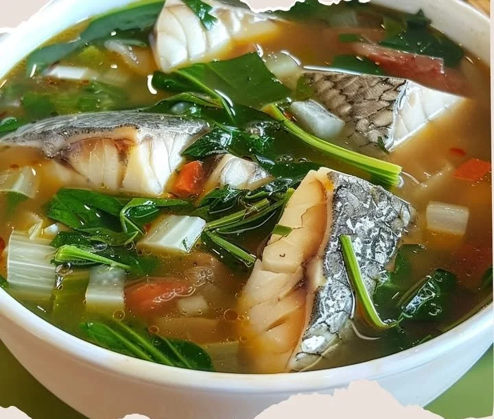 Bowl of delicious fish soup with fresh vegetables and herbs