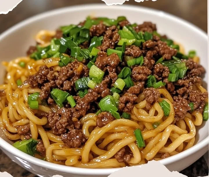 Plate of Mongolian Ground Beef Noodles garnished with green onions and sesame seeds